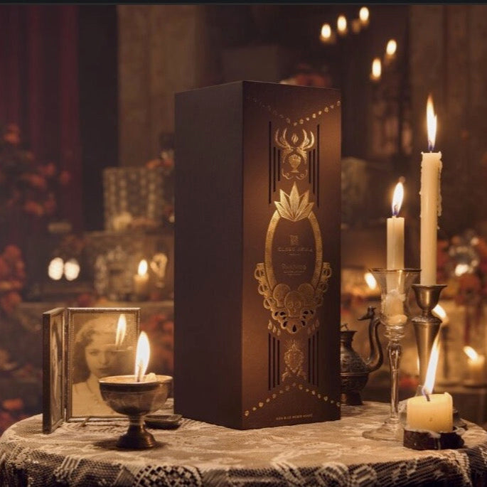 Decorative box with intricate design on a table surrounded by candles in a warm, dimly lit setting.
